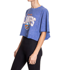 Load image into Gallery viewer, Woman standing sideways in front of a white background wearing an oversized, blue, acid wash crop top - featuring a New York Islanders logo in the center of the shirt.
